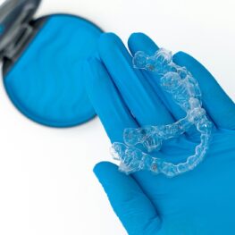 Blue gloved hand holding Invisalign aligners